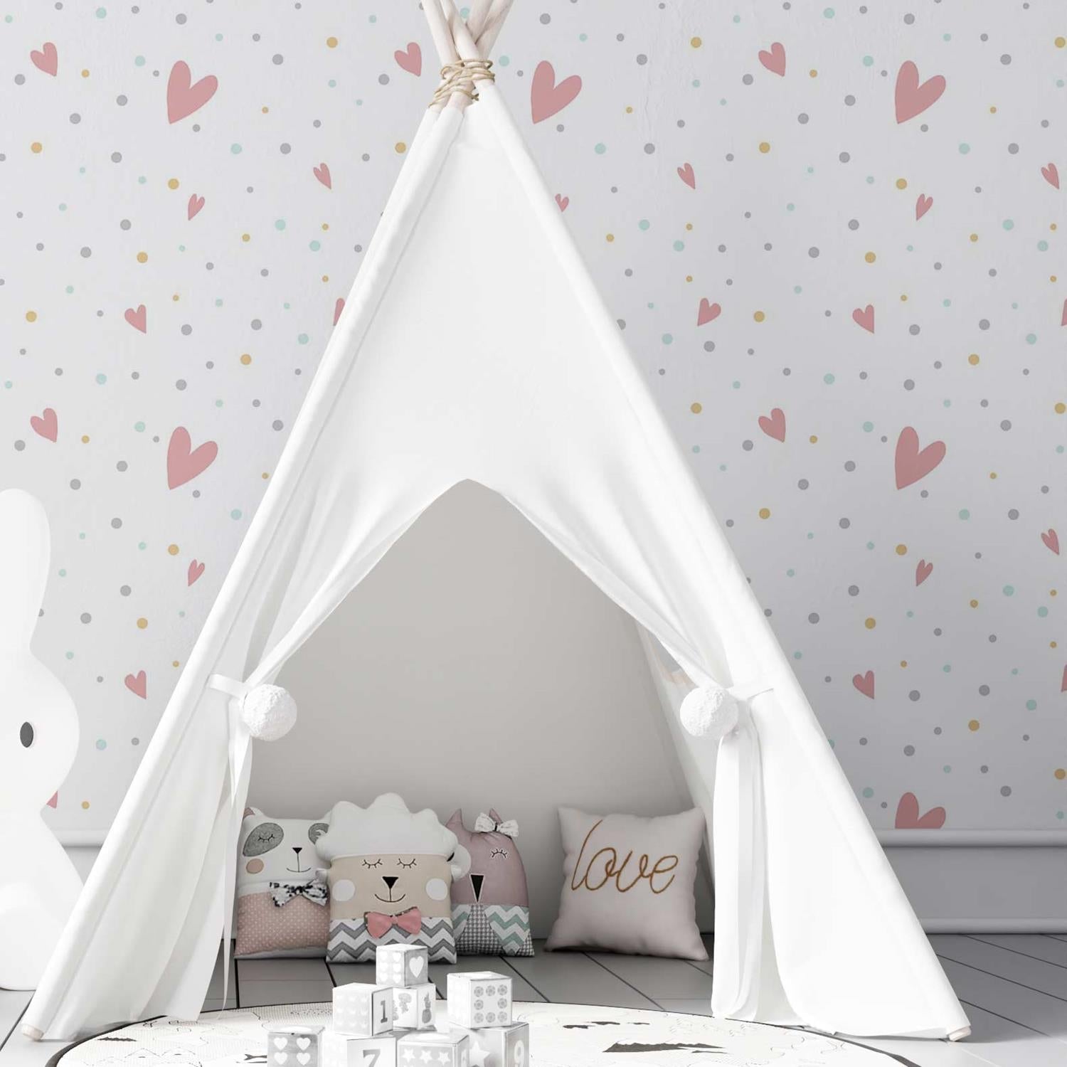 tenda caseira montada em frente ao papel de parede branco com bolinhas e corações coloridos